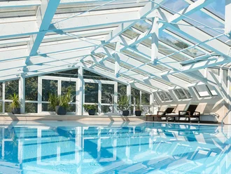 Modernes Hallenbad mit Glasdach im Hotel Schwedi – lichtdurchfluteter Wellnessbereich mit Blick ins Grüne.