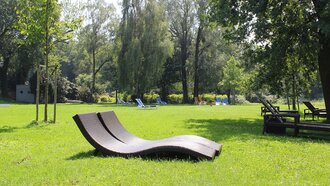 Design-Liege auf sonniger Liegewiese im Garten des Hotel Schwedi – entspannen unter Bäumen in natürlicher Ruhezone am Bodensee.