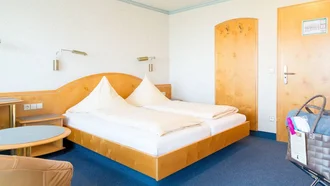 Helles Doppelzimmer im Hotel Schwedi mit Holzmöbeln, Teppichboden und liebevollen Details.