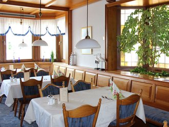 Elegant gedeckte Tische im Restaurant des Hotel Schwedi mit Holzvertäfelung, Tageslicht und gemütlichem Ambiente – stilvoll speisen in familiärer Atmosphäre.
