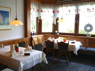 Heller Gastraum im Hotel Schwedi mit weiß gedeckten Tischen, Fensterfront und gemütlicher Eckbank – traditionelles Ambiente mit liebevollen Details.