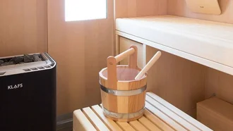 Modern ausgestattete Sauna im Hotel Schwedi mit Holzverkleidung, Aufgusseimer und natürlichem Licht.