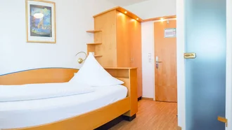 Kleines Einzelzimmer im Hotel Schwedi mit hellem Holzmobiliar, platzsparender Einrichtung und freundlicher Atmosphäre – ideal für Alleinreisende.