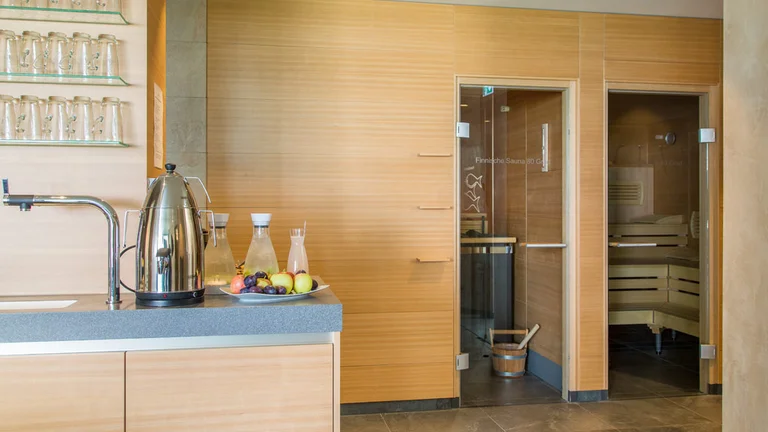 Saunabereich im Hotel Schwedi mit moderner Teestation, Getränken und Zugang zur Holzsauna – Entspannung und Erholung in stilvollem Ambiente.
