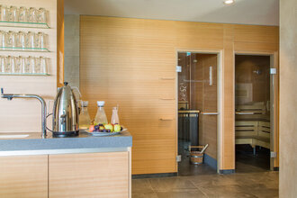 Saunabereich im Hotel Schwedi mit moderner Teestation, Getränken und Zugang zur Holzsauna – Entspannung und Erholung in stilvollem Ambiente.