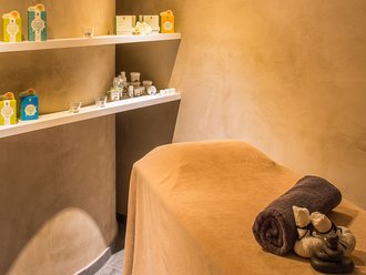 Massageraum im Hotel Schwedi mit weicher Liege, Pflegeprodukten und stimmungsvoller Beleuchtung – entspannende Atmosphäre für wohltuende Behandlungen.