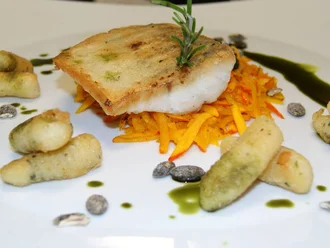 Gebratenes Fischfilet auf Karottenjulienne mit hausgemachten Gnocchi, Pistazien und Kräuteröl – kunstvoll angerichtetes Hauptgericht im Hotel Schwedi.