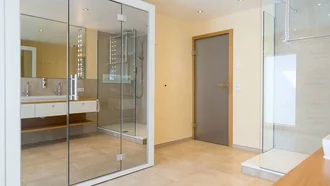 Modernes Badezimmer in der Franzl Suite des Hotel Schwedi mit großer Glasdusche, Doppelwaschtisch und hellem Fliesenboden.