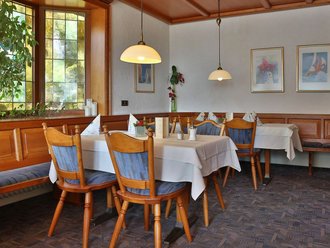 Elegant gedeckte Tische im Restaurant des Hotel Schwedi mit Holzvertäfelung, Tageslicht und gemütlichem Ambiente – stilvoll speisen in familiärer Atmosphäre.