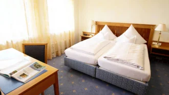 Die helle Elizabeth Suite im Hotel Schwedi mit großem Fenster, Schreibtisch und klassischer Einrichtung – ideal für erholsame Aufenthalte und ruhiges Arbeiten am Bodensee.

