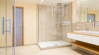 Wellness-Badezimmer in der Franzl Suite des Hotel Schwedi mit großer Glasdusche, modernem Waschtisch mit Ablage und stilvoller Beleuchtung.