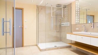 Franzl Suite Wellness-Badezimmer in der Franzl Suite des Hotel Schwedi mit großer Glasdusche, modernem Waschtisch mit Ablage und stilvoller Beleuchtung.