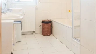 Helles Badezimmer in einer Ferienwohnung des Hotel Schwedi mit Badewanne, zwei Waschbecken und großzügigem Grundriss – ideal für Paare oder Familien.