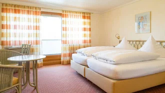 Hell eingerichtetes Doppelzimmer im Hotel Schwedi mit Balkon, Sitzgruppe und freundlicher Atmosphäre.