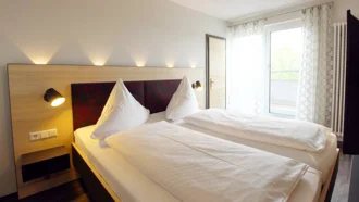 Modernes Doppelzimmer im Hotel Schwedi mit Balkonzugang und klarer Linienführung – lichtdurchfluteter Raum mit viel Bewegungsfreiheit.