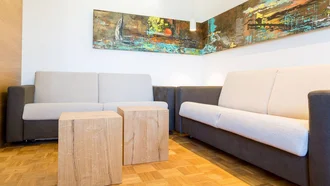 Wohnbereich der Franzl Suite im Hotel Schwedi mit zwei Sofas, modernem Wandbild und Holzelementen.