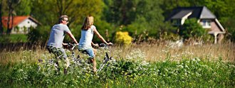 Zwei Radfahrer auf einem Weg durch blühende Wiesenlandschaft nahe dem Hotel Schwedi – aktiver Naturgenuss in idyllischer Umgebung.