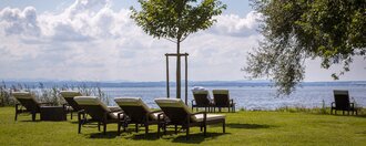 Liegestühle auf der sonnigen Uferwiese des Hotel Schwedi mit Blick auf den Bodensee – ruhiger Rückzugsort inmitten von Natur und Weitblick.