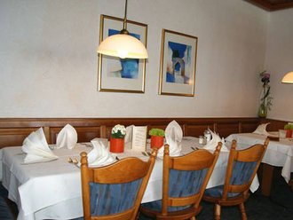Gedeckte Tische mit Stoffservietten in der Schwedenstube des Hotel Schwedi, umrahmt von Holzvertäfelung, Wandbildern und warmem Licht – gemütliche Atmosphäre für Genussmomente.