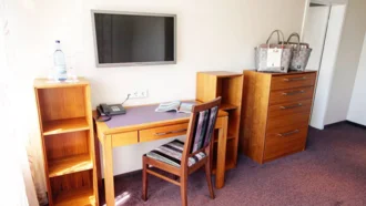 Schreibtischecke in der Theresia Suite des Hotel Schwedi mit Massivholzmöbeln, Flachbild-TV und Willkommenskorb – funktional und charmant eingerichtet.