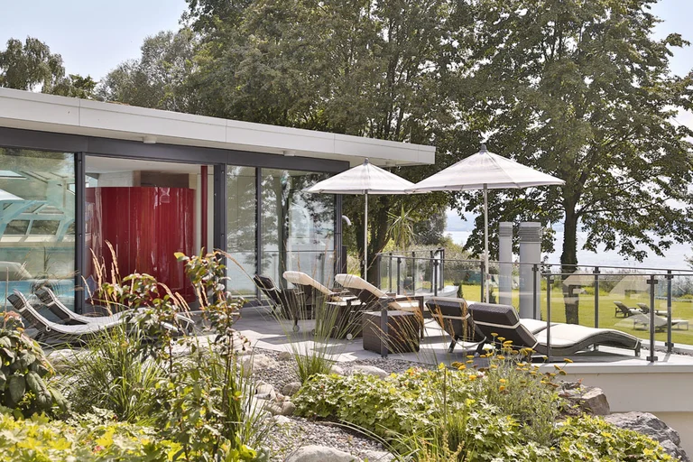 Sonnenterrasse des Wellnessbereichs im Hotel Schwedi mit Liegestühlen, Sonnenschirmen und Blick ins Grüne – entspannen in naturnaher Ruhezone am Bodensee.