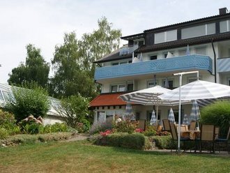 Seitenansicht des Hotel Schwedi mit Balkonzimmern, Sonnenterrasse und blühender Gartenanlage – harmonisches Zusammenspiel von Natur und Komfort am Bodensee.